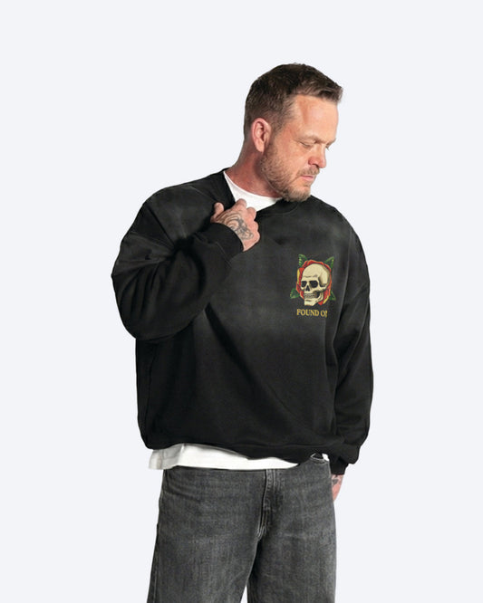 Man wearing a black sweatshirt with a skull logo on a white background