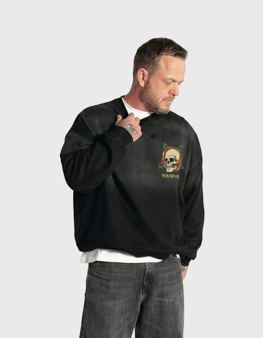 Man wearing a black sweatshirt with a skull logo on a white background