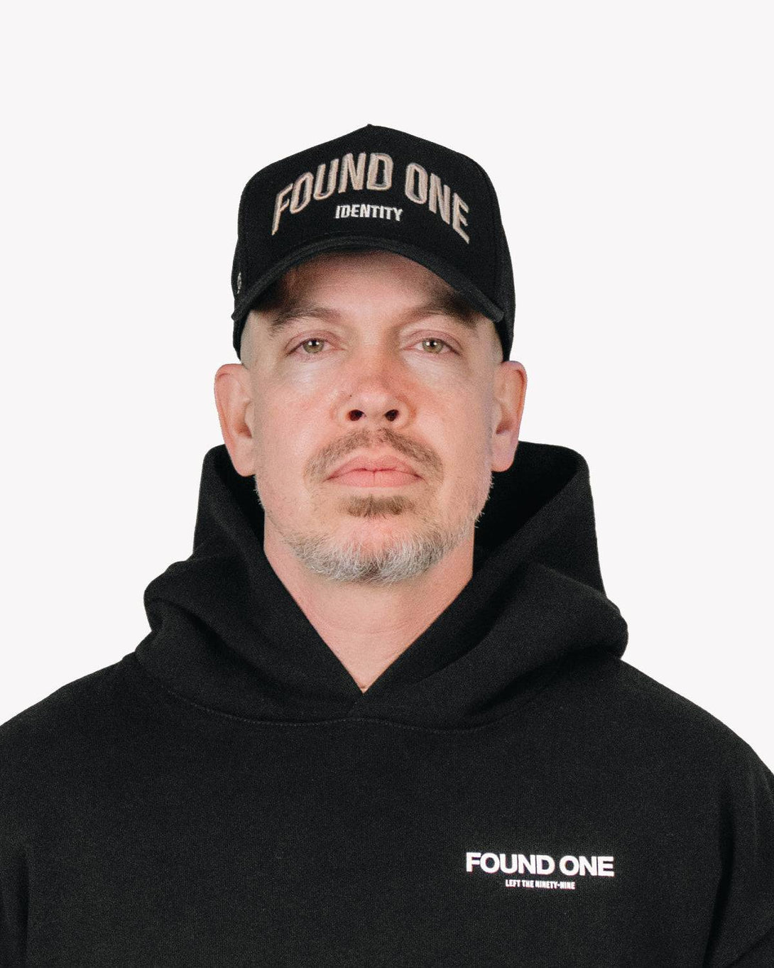 Front-facing view of a man wearing the Found One Identity Cap. Black snapback hat with bold embroidered branding and structured fit.