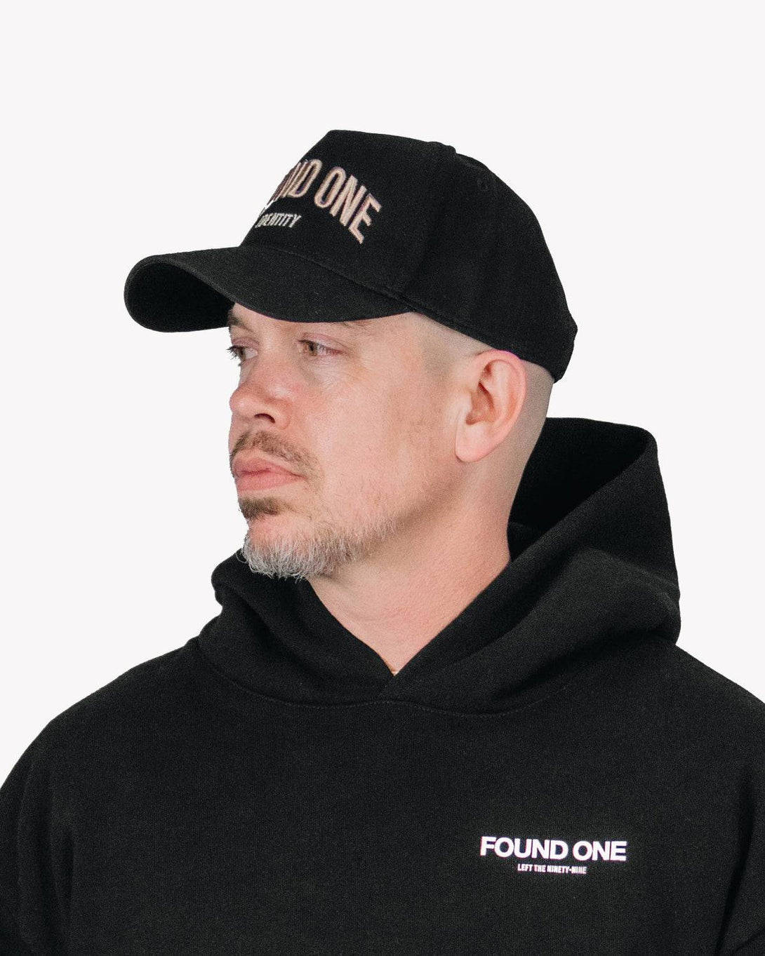 Side profile of a man wearing the Found One Identity Cap. Black A-frame snapback with faith-inspired embroidery details.