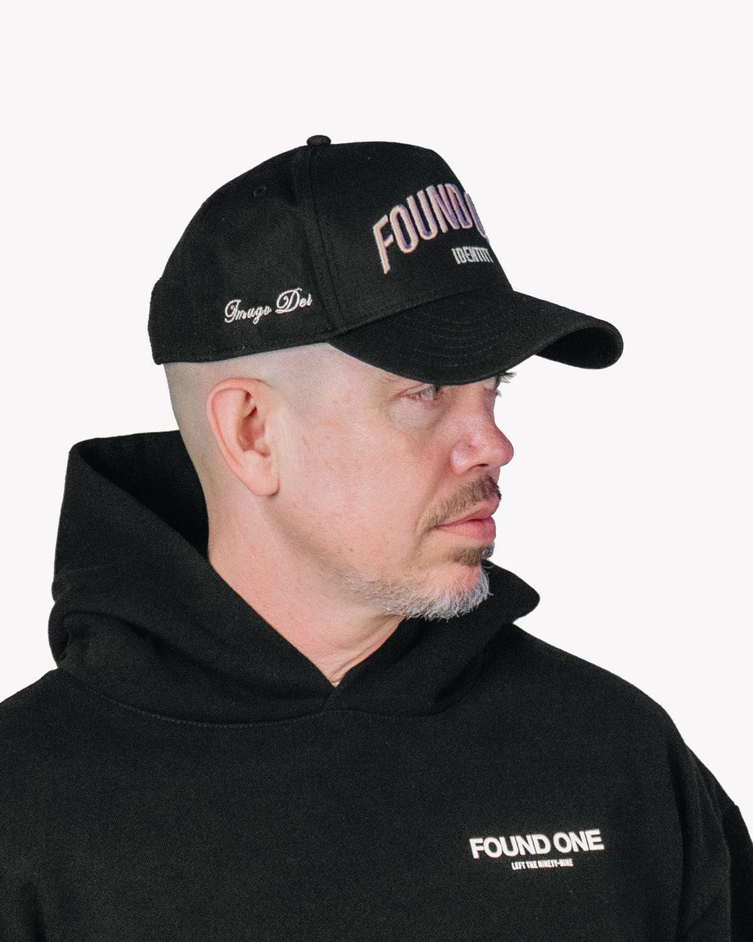 Man wearing the Found One Identity Cap in black. Snapback hat with bold embroidery, paired with a matching black hoodie.